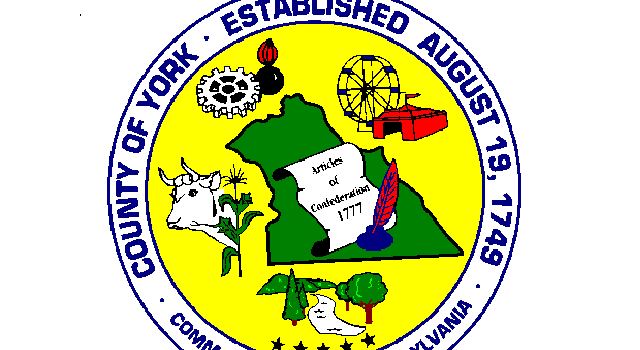 This is the York County Logo. Yellow circle with a green outline of York County, PA. Picture of a cow on the left, picture of a ferris wheel top right.