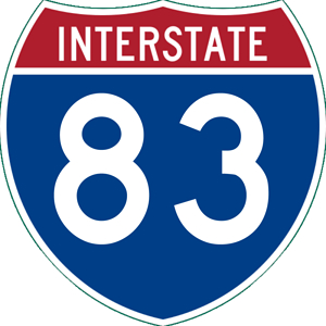 Picture of an Interstate sign shaped like a crest. Top part is in red with white text, "INTERSTATE". The bottom part is blue with white text, "83".