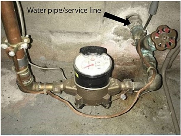 A picture of a water pipe and service line in a basement.
